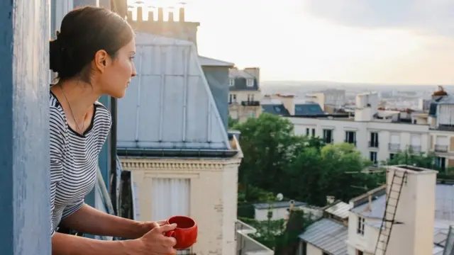 mulher tomando café na janela