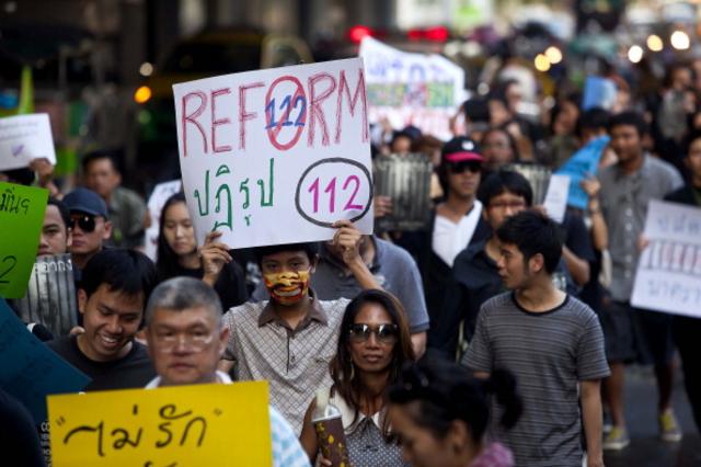 นักเคลื่อนไหวถือป้ายเรียกร้องให้ปฏิรูปกฎหมายอาญามาตรา 112 ของไทยในการเดินขบวนต่อต้านกฎหมายนี้ในกรุงเทพฯ เมื่อวันที่ 10 ธ.ค. 2554