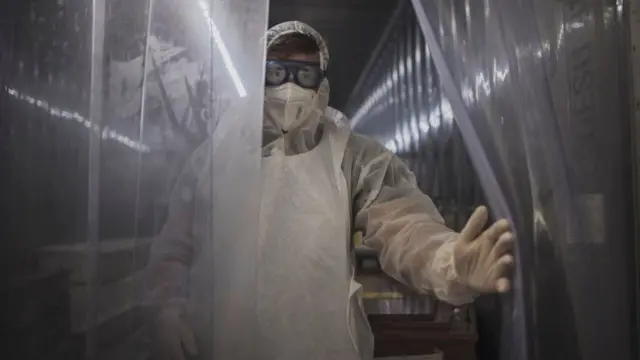 A morgue attendant at the Johannesburg branch of the South African funeral and burial services company Avbob keeps the curtain open from inside a refrigerated container where bodies of patients deceased with COVID-19 related illnesses are kept isolated ahead of their burials on January 22, 2021.