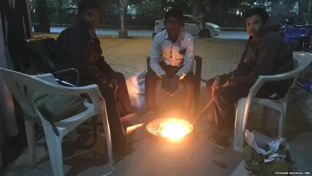 सर्दी से बचने के लिए आग जलाकर बैठे चौकीदार
