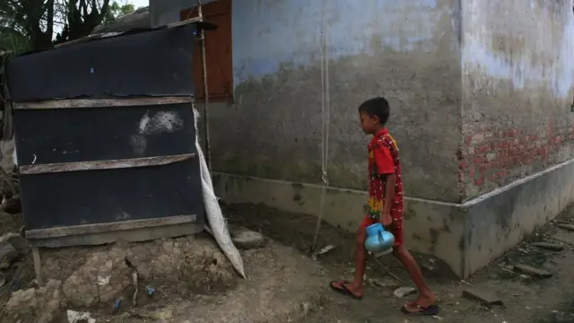 Boy preparing to use a makeshift bathroom in Bangladesh