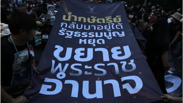 ผู้ชุมนุมกลุ่มราษฎรถือป้ายเรียกร้องการหยุดขยายพระราชอำนาจระหว่างเดินขบวนจากสามย่านไปสถานทูตเยอรมนีวันนี้ (26 ต.ค.)