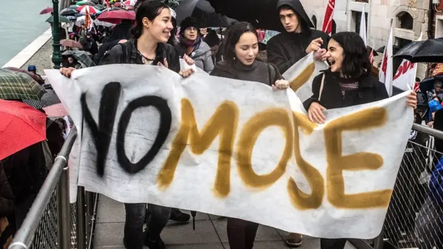 사람들이 모세 프로젝트에 반대하는 플래카드를 들고 걷고 있다