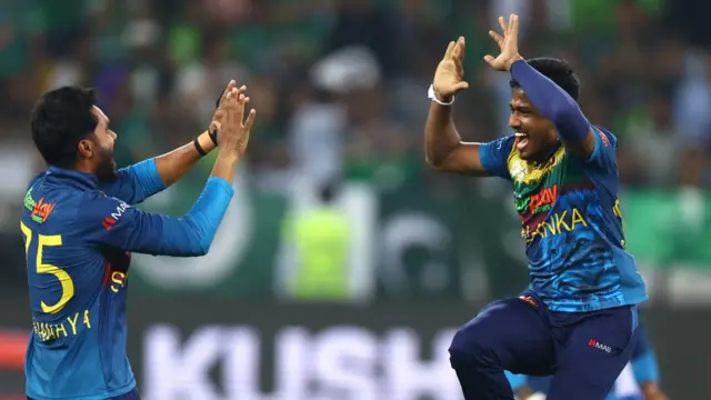 Two Sri Lanka cricketers high-five and celebrate a wicket against Pakistan as they win the Asia Cup