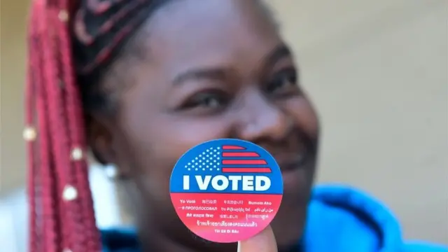 Mujer muestra su pegatina de que votó.
