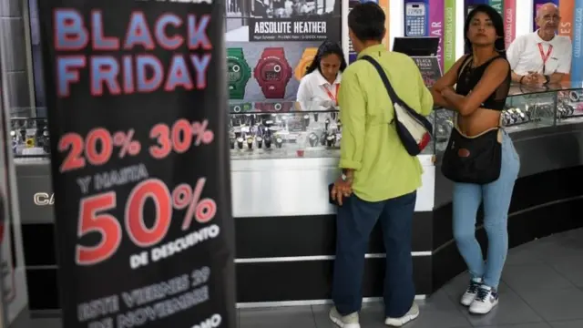 Un hombre y una mujer en una tienda de relojes con ofertas por el Black Friday