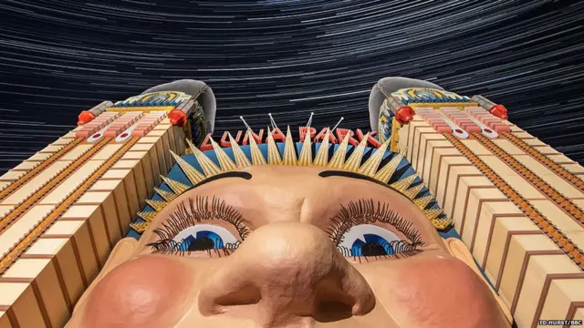 An image showing a park entrance featuring a large face with stars in the sky above