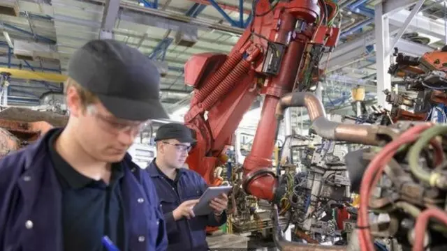 روبوت يعمل بجوار عمال في مصنع