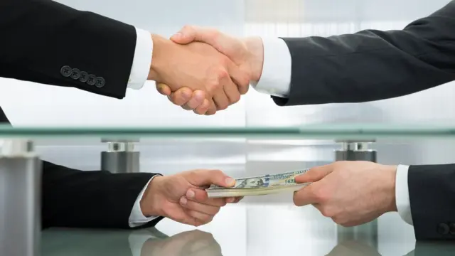 Entrega de dinero bajo la mesa.