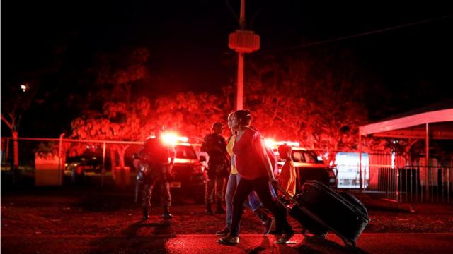 À noite, mulheres passam com malasjogo da roletinha que ganha dinheirofrente a agentesjogo da roletinha que ganha dinheirosegurança e viaturas