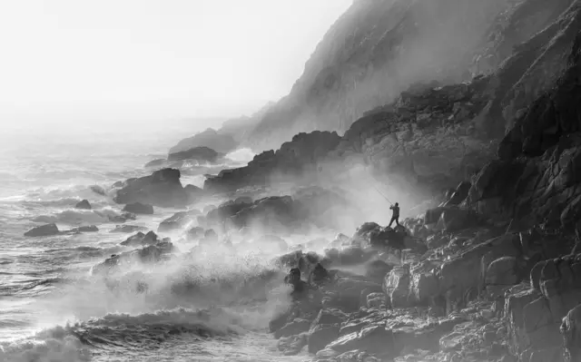Fisherman on Rocks in Strong Westerly Winds Porth Nanven, Cornwall