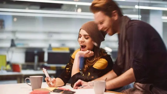 Dos jóvenes una oficina que hablan y se ríen