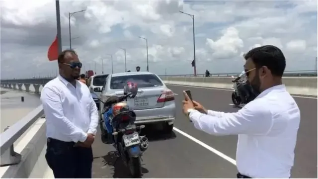 সেতুর উপর মোটরসাইকেল থামিয়ে ছবি তুলছেন দুই যাত্রী