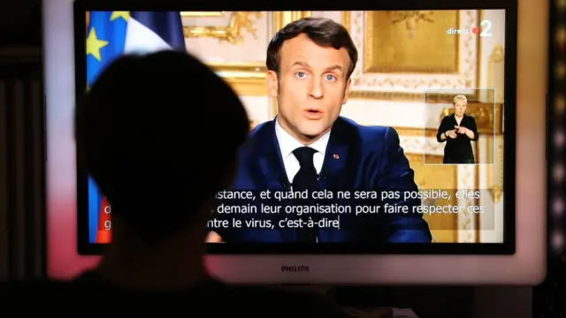 French President Emmanuel Macron is seen on a television screen as he speaks during a televised address to the nation on the outbreak of COVID-19, caused by the novel coronavirus, on March 16, 2020, in Paris.