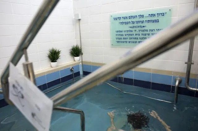 Una mujer judía se sumerge en las aguas de un mikveh, en Jerusalén. 17 de abril de 2019. (Foto de Heidi Levine para la BBC).