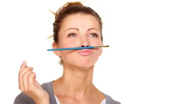 Una mujer que mira al horizonte, con un lápiz entre el labio superior y la nariz