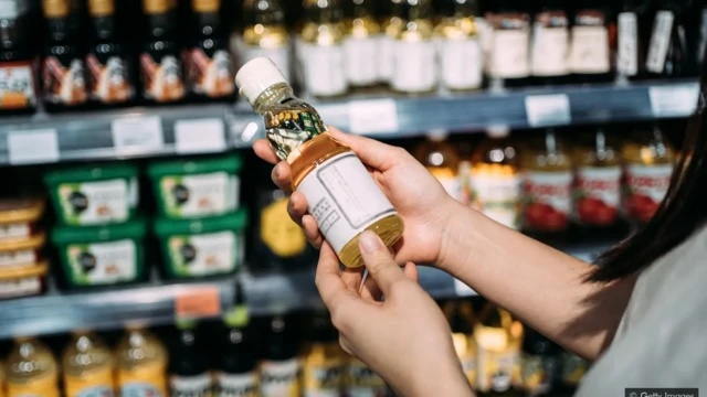 Une femme achète une bouteille d'huile dans un supermarché