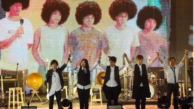 舞台上播放五月天20周年的＂成长历程＂。