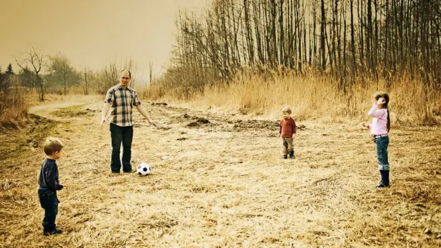 Отец играет в футбол с детьми