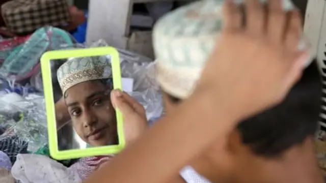 ਭਾਰਤੀ ਜੰਮੂ ਕਸ਼ਮੀਰ ਵਿੱਚ ਇੱਕ ਲੜਕਾ ਨਮਾਜ਼ ਲਈ ਟੋਪੀ ਲੈਣ ਸਮੇਂ ਸ਼ੀਸ਼ਾ ਦੇਖਦਾ ਹੋਇਆ।