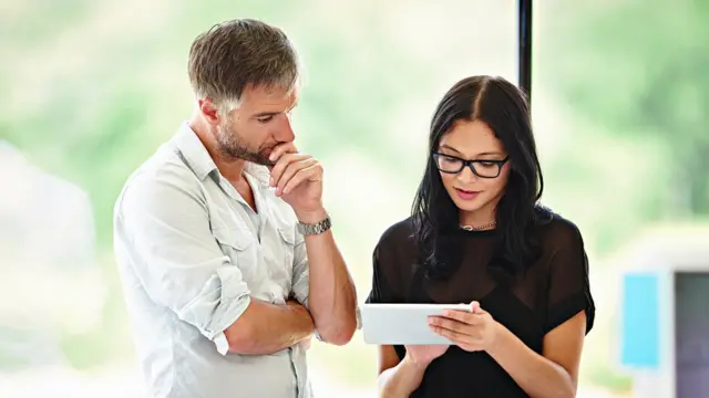 Homem conversando com mulher enquanto ela usa um tablet