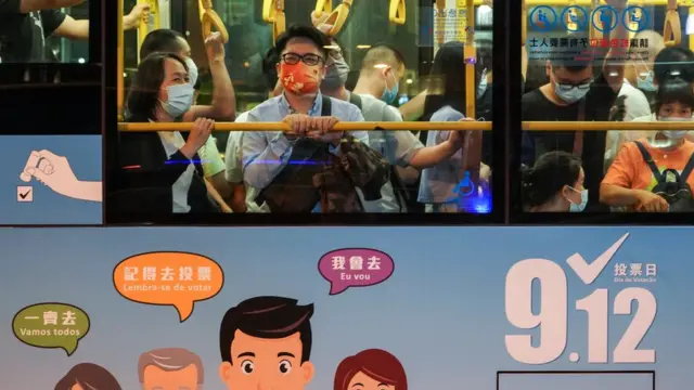 澳門孫逸仙大馬路一輛巴士上站立的乘客看著窗外景色（中新社照片10/9/2021）