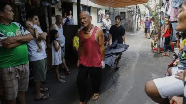 Petugas membawa jenazah terduga penjahat narkoba di Quezon City, timur Manila pada tanggal 30 Mei 2018.