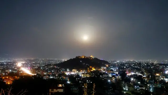 A full moon rises behind the Swayambhunath Stupa in Kathmandu, Nepal, 31 March 2018.