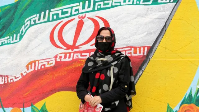 ઇરાનના ઝંડા પાસે મહિલાની તસવીર