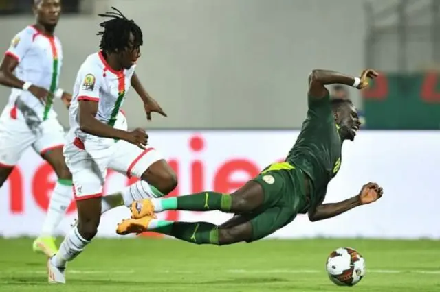 Sadio Mane go down inside di box during di match as Burkina Faso player challenge
