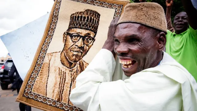 Wani magoyin bayan shugaban rike da hotonsa cikin annashuwa