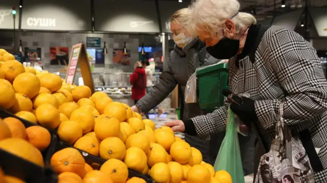 Deux femmes se tenants devant un étal sur lequel sont exposé d'oranges