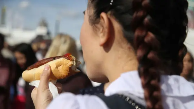 Seorang gadis makan hot dog.