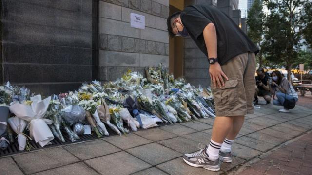 英国驻香港总领事馆外一位男士向市民留下悼念英女王伊丽莎白二世的花堆鞠躬（9/9/2022）