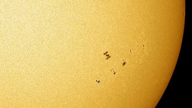 A silhueta da Estação Espacial Internacional contra o Sol