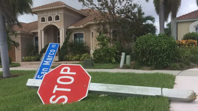 Cartel de "stop" tirado en el jardín frente a la entrada a una casa.