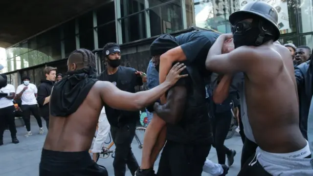 Amigos protegem Hutchinson, que carrega um manifestante branco