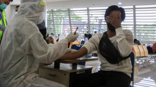 Sejumlah Pekerja Migran Indonesia (PMI) asal Malaysia menjalani Rapid Test saat tiba di kedatangan Internasional Terminal 2 Bandara Juanda, Sidoarjo, Jawa Timur, Selasa (07/04).