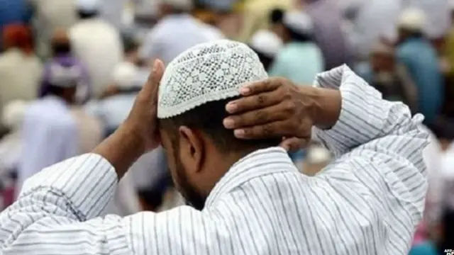 ਇੱਕ ਮੁਸਲਮਾਨ ਆਪਣੀ ਟੋਪੀ ਠੀਕ ਕਰਦੇ ਹੋਏ