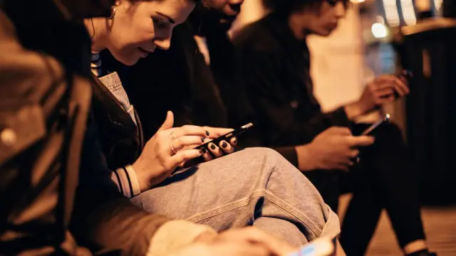 أشخاص ينظرون إلى هواتفهم الذكية