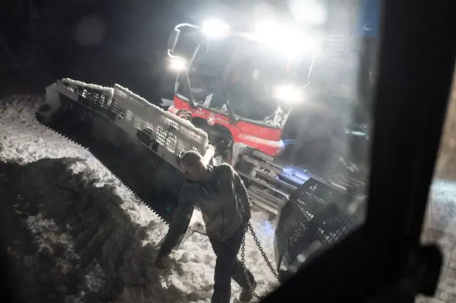 عضو بفريق صيانة مضامير التزلج يقوم بعمله.