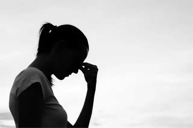 Silueta de una mujer agarrándose la cabeza