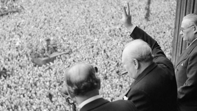 Winston Churchill desde un balcón, saluda a una multitud