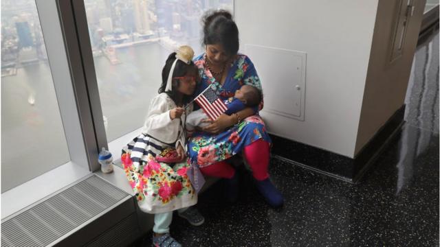 一名孟加拉移民与孩子参加了一个入籍美国仪式。她的孩子手里举着一面美国国旗。