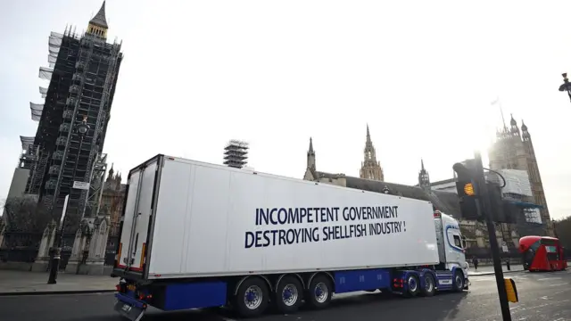 تریلی یک شرکت ماهیگیری با پیام 'دولت بی‌کفایت صنعت صید سخت‌پوستان را نابود می‌کند' در مقابل پارلمان بریتانیا