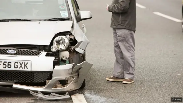 رجل يقف إلى جوار سيارة محطمة المقدمة