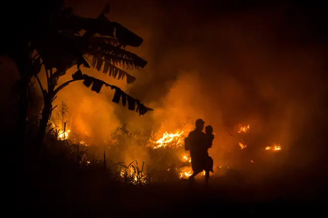 A man carries his son as he walks through the haze on the way to his house as a fire burned peatland in 2015 fires.