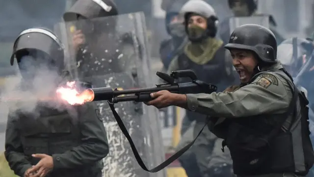 Um membro da Guarda Nacional venezuelana disparando arma