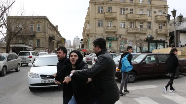 Двое в штатском ведут молодого человека