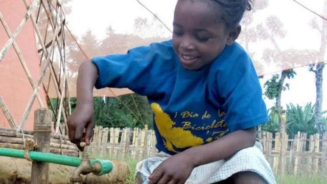 Un niño sacando agua de un caño